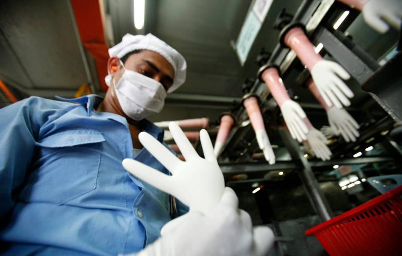 A worker inspects a glove at the factory of Top Glove in Kelang, outside Kuala Lumpur September 25, 2009. REUTERS/FILE PHOTO
