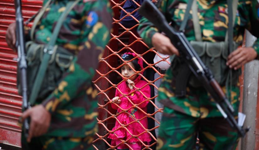 This Jan 5, 2014 photo shows a toddler watching Bangladesh Army members patrolling in front of a polling station in capital Dhaka during the 10th national election. FILE PHOTO/ Mahmud Hossain Opu