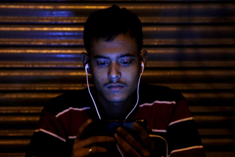 A man in India watches a movie on his mobile phone in New Delhi, India, November 16, 2016. REUTERS/FILE PHOTO