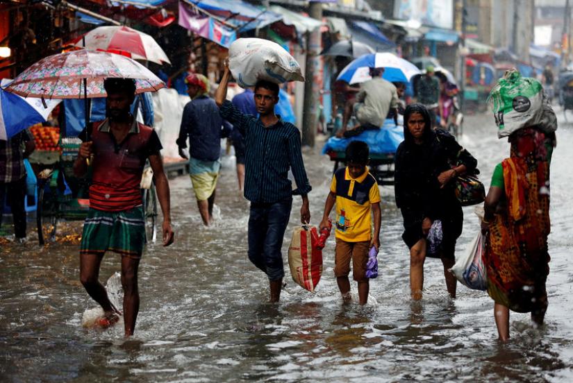 People walk on the water as roads are flooded due to heavy rain in Dhaka, Bangladesh July 26, 2017. REUTERS