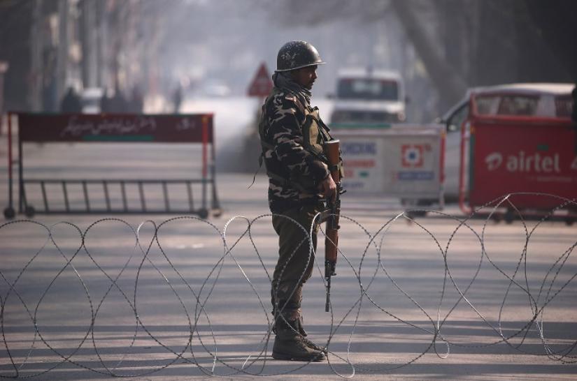 An Indian policeman stands guard behind concertina wire laid across a road leading to the Indian army headquarters in Srinagar December 17, 2018. REUTERS