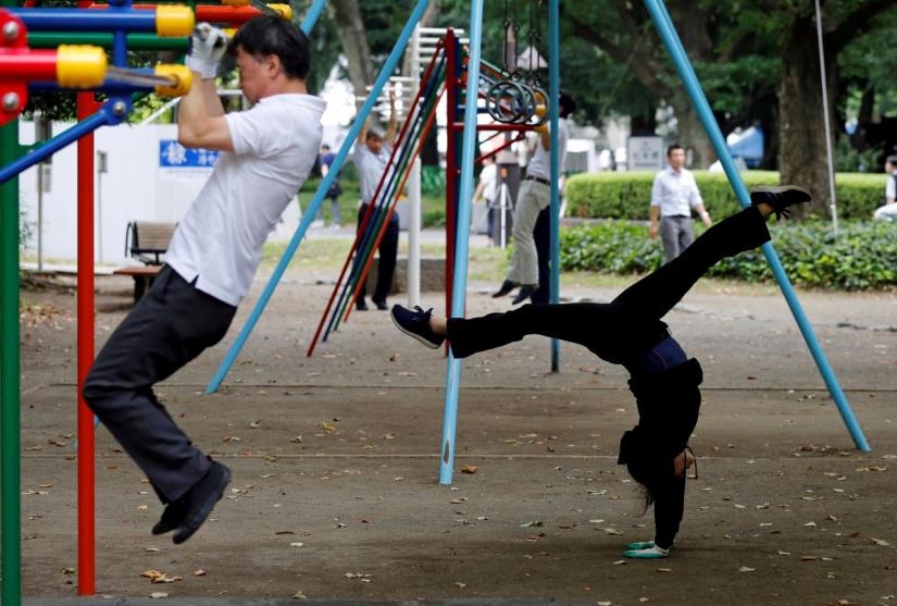 Office workers exercise during their lunch break at a park in central Tokyo, Japan September 22, 2017. REUTERS/FILE PHOTO