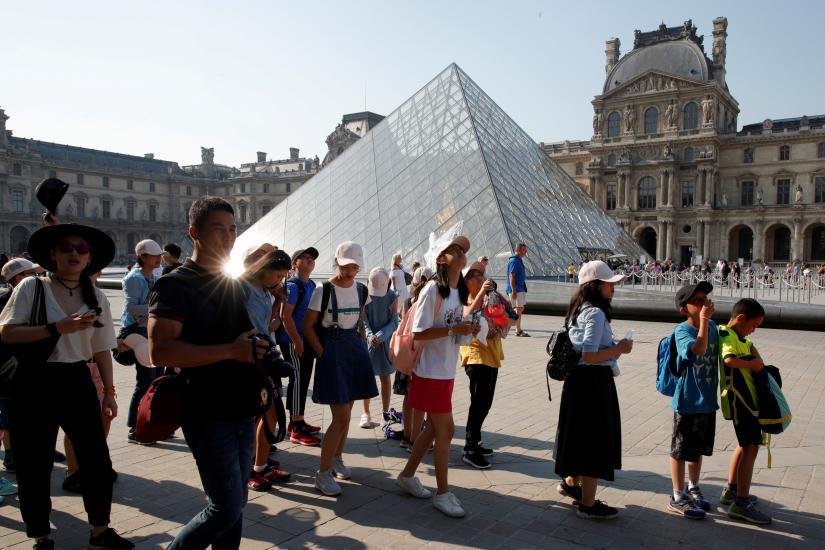 Chinese tourists stand in front of the Louvre Pyramid designed by Chinese-born U.S. Architect Ieoh Ming Pei outside the Louvre Museum in Paris, France, July 26, 2018. Picture taken July 26, 2018. REUTERS/File Photo