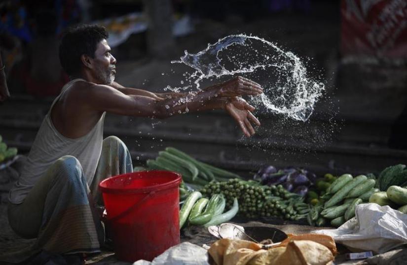 A vendor splashes water as he sells vegetable next to a railway track in Dhaka May 29, 2014. REUTERS