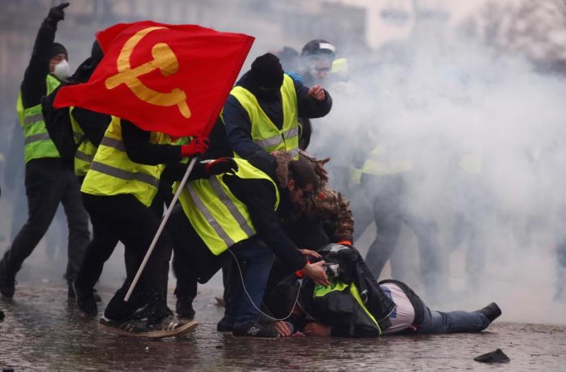 Protesters wearing yellow vests help a person injured by a water cannon during a demonstration by the `yellow vests` movement near the Arc de Triomphe in Paris, France, January 12, 2019. REUTERS