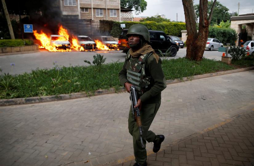 A member of security forces walks as cars are seen on fire at the scene where explosions and gunshots were heard at the Dusit hotel compound, in Nairobi, Kenya January 15, 2019. REUTERS
