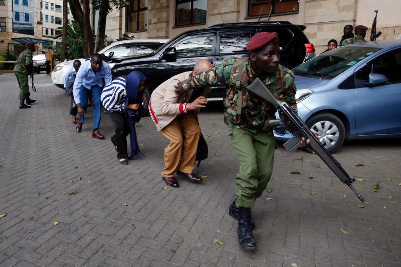 People are evacuated by a member of security forces at the scene where explosions and gunshots were heard at the Dusit hotel compound, in Nairobi, Kenya January 15, 2019. REUTERS