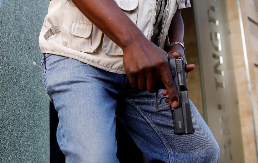 A member of security forces holds a pistol at the scene where explosions and gunshots were heard at the Dusit hotel compound, in Nairobi, Kenya January 15, 2019. REUTERS