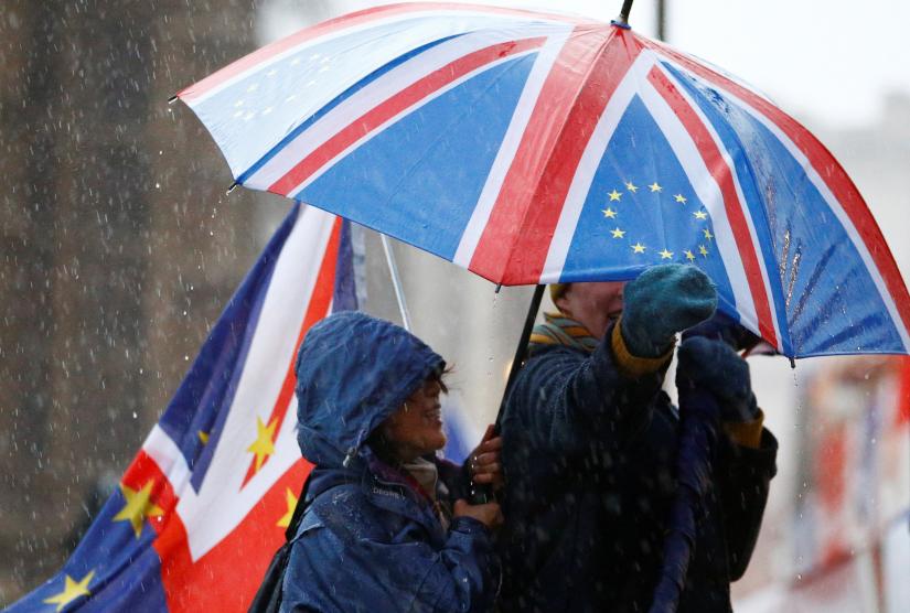 Anti-Brexit protesters shelter from the rain outside the Houses of Parliament, after Prime Minister Theresa May`s Brexit deal was rejected, in London, Britain, January 16, 2019. REUTERS