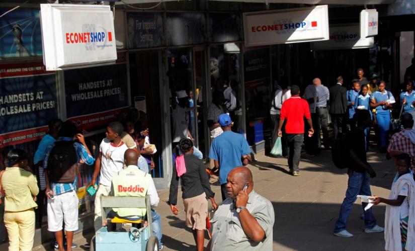 A Zimbabwean man speaks on his phone outside a branch of mobile service provider Econet Wireless in central Harare, June 6, 2014. REUTERS/File Photo