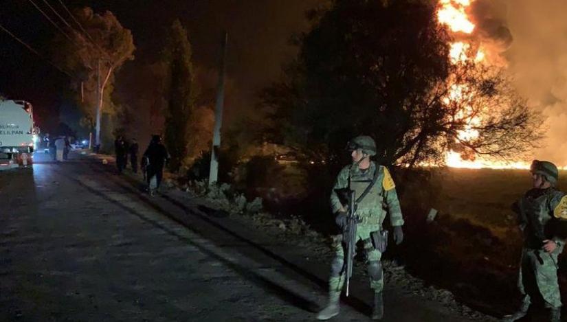 Military personnel watch as flames engulf an area after a ruptured fuel pipeline exploded, in the municipality of Tlahuelilpan, Hidalgo, Mexico, near the Tula refinery of state oil firm Petroleos Mexicanos (Pemex), January 18, 2019 in this handout photo provided by the National Defence Secretary (SEDENA). National Defence Secretary/Handout via REUTERS.