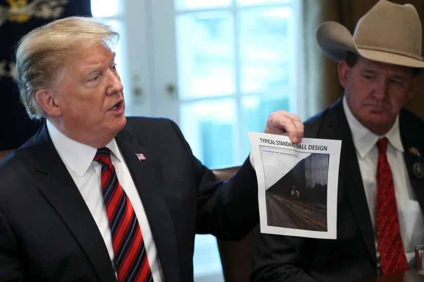 US President Donald Trump shows a photo of a `typical` border wall design during a `roundtable discussion on border security and safe communities` with state, local, and community leaders in the Cabinet Room of the White House in Washington, U.S., January 11, 2019. REUTERS