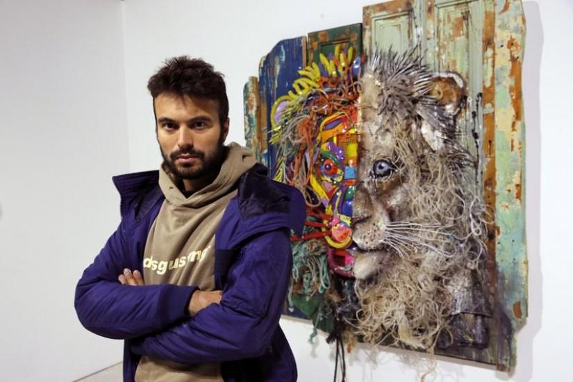 Street artist Bordalo II poses next to one of his creation `Half Lion` (2018) prior to the opening of his exhibition in Paris, France, January 22, 2019.REUTERS