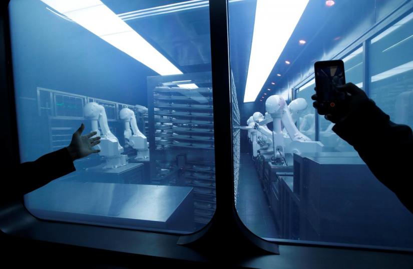 A customer takes a picture as robotic arms collect pre-packaged dishes from a cold storage, done according to the diners` orders, at Haidilao`s new artificial intelligence hotpot restaurant in Beijing, China on Nov 14, 2018. REUTERS/File Photo