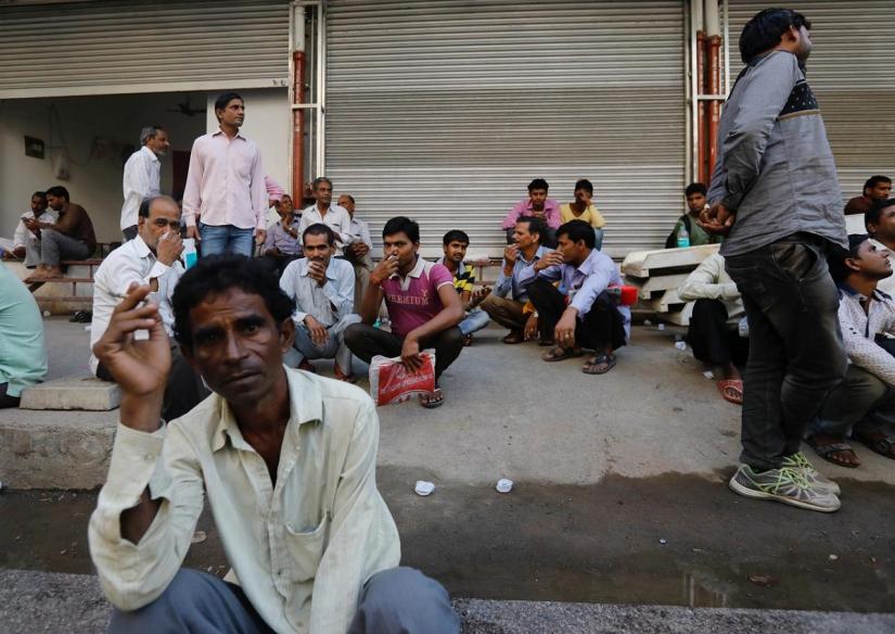 Tradespeople sit on the side of a road as they wait to get hired for work in Mumbai, India, November 6, 2017. REUTERS
