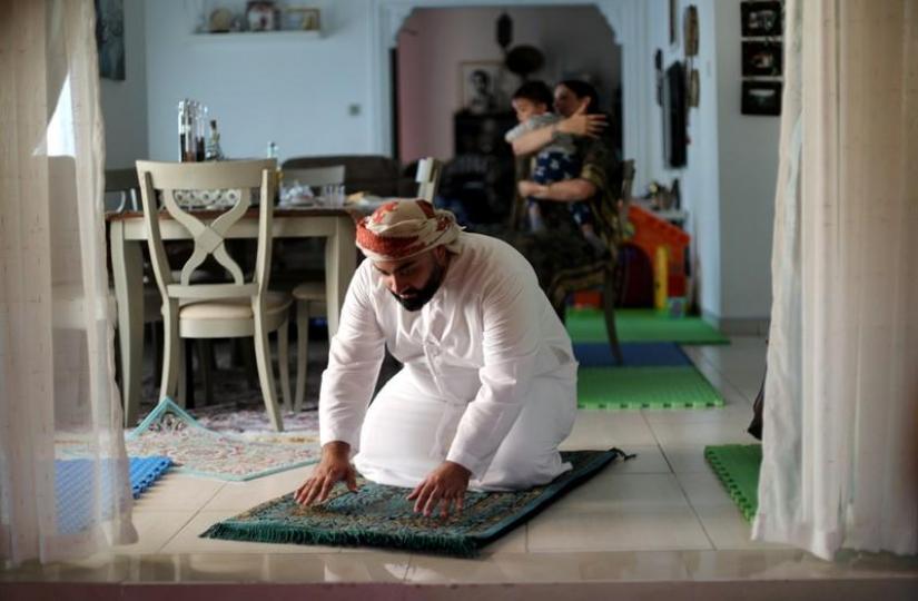 Ali al Sayed, local Muslim, prays as his wife Mina Liccione, a Catholic Christian, holds their child at their house in Jebel Ali, in Dubai, United Arab Emirates, January 28, 2019. REUTERS/File Photo