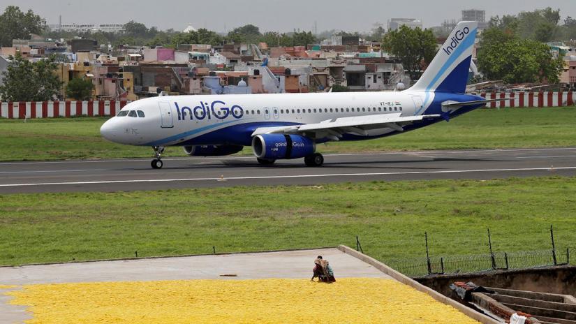 Women spread fryums for drying on a rooftop as an IndiGo Airlines Airbus A320-200 aircraft moves on the runway after landing at the Sardar Vallabhbhai Patel international airport in Ahmedabad, July 6, 2017. REUTERS/Files