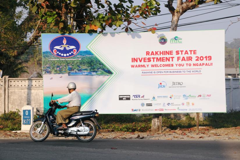 A rider passes by the Rakhine State Investment Fair 2019 bulletin board in Ngapali beach in Thandwe, Rakhine State, Myanmar February 19, 2019. Picture taken February 19, 2019. REUTERS