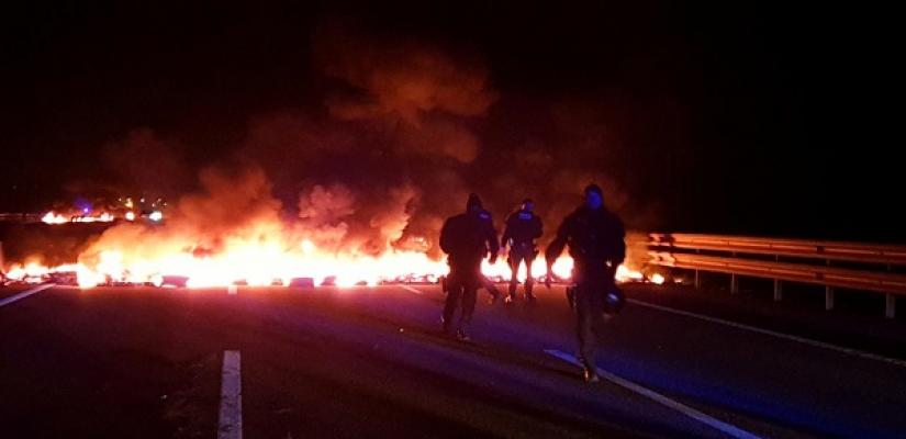 Police officers stand next to burning barricades settled to block the AP7 highway during a regional strike near Girona, Spain, February 21, 2019. REUTERS
