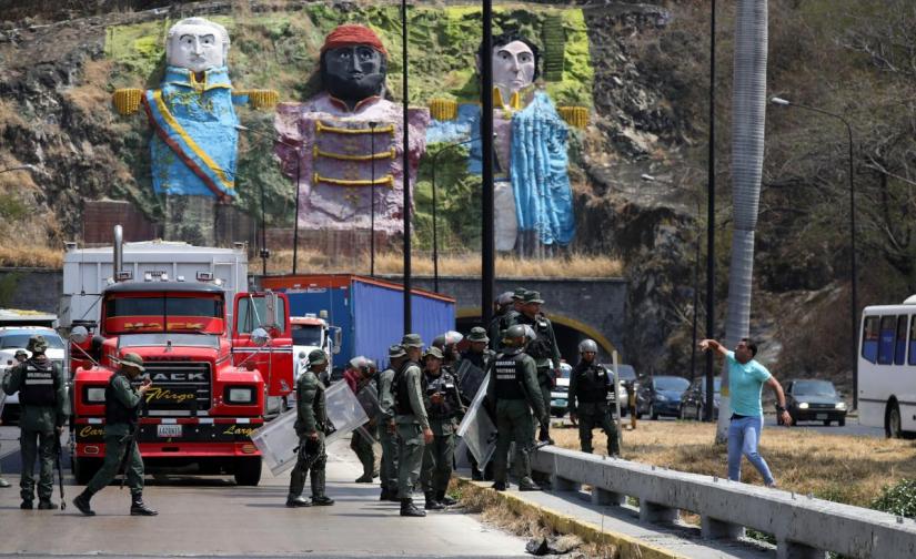 Security forces block the road as they clash with lawmaker members of the Venezuelan National Assembly and supporters of the Venezuelan opposition leader Juan Guaido, who many nations have recognised as the country`s rightful interim ruler, on the outskirts of Mariara, Venezuela February 21, 2019. REUTERS