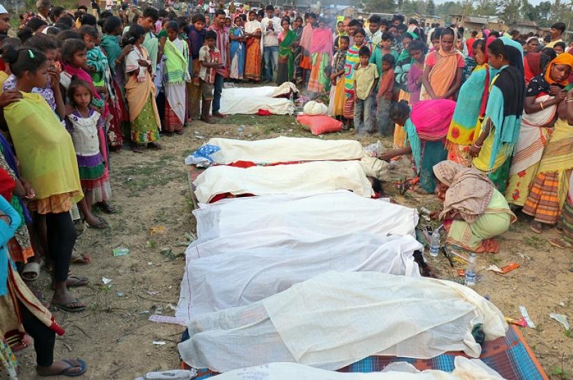 People stand next to the bodies of tea plantation workers, who died after consuming bootleg liquor, in Golaghat in the northeastern state of Assam, India, Feb 22, 2019. REUTERS
