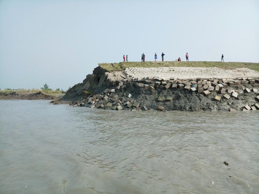 Islanders stand on an embankment on Hatiya Island that is crumbling into the sea due to erosion in Noakhali District, Bangladesh, Oct. 22, 2018, Thomson Reuters Foundation