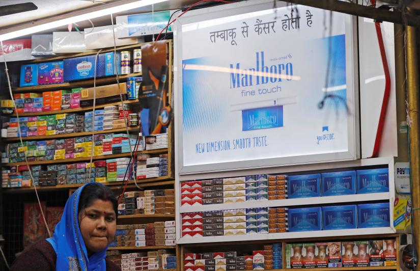 A woman waits for customers as a Marlboro advertisement pasted inside her stall in New Delhi, India March 6, 2019. REUTERS