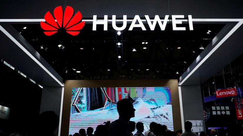 People walk past a sign board of Huawei at CES (Consumer Electronics Show) Asia 2018 in Shanghai, China Jun 14, 2018. REUTERS/File Photo