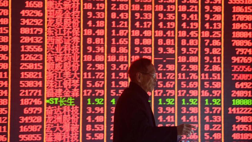 A man is seen in front of an electronic board showing stock information on the first day of trading in the Year of the Pig, following the Chinese Lunar New Year holiday, at a brokerage house in Hangzhou, Zhejiang province, China February 11, 2019. REUTERS/File Photo