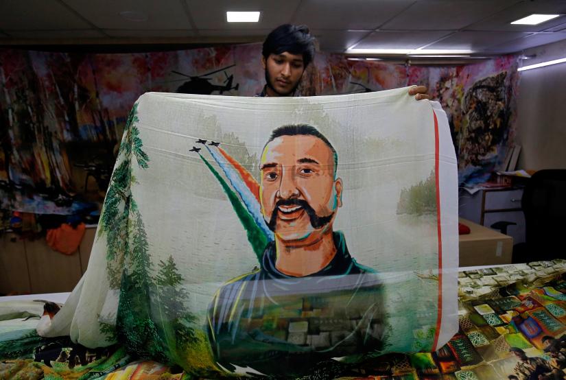A salesman displays a sari, a traditional clothing worn by women, with a printed image of Indian Air Force pilot Abhinandan Varthaman, who was captured and later released by Pakistan, inside a sari manufacturing factory in Surat, India, March 8, 2019. REUTERS