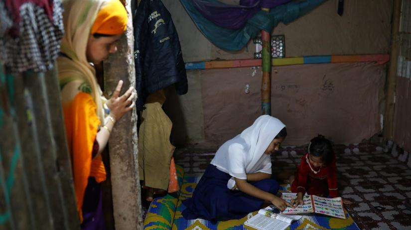 Yasmin, a Rohingya girl who was expelled from Leda High School for being a Rohingya, helps her younger sister to study in Leda camp in Teknaf, Bangladesh, March 5, 2019. REUTERS