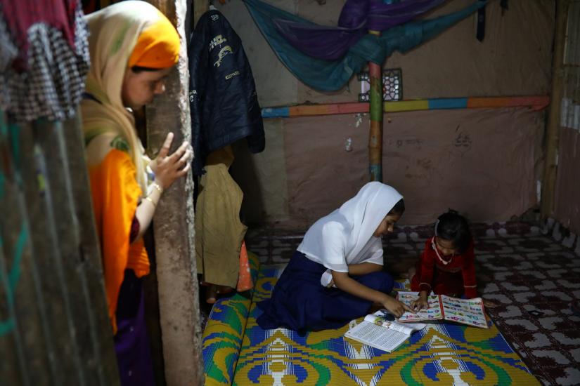 Yasmin, a Rohingya girl who was expelled from Leda High School for being a Rohingya, helps her younger sister to study in Leda camp in Teknaf, Bangladesh, March 5, 2019. REUTERS