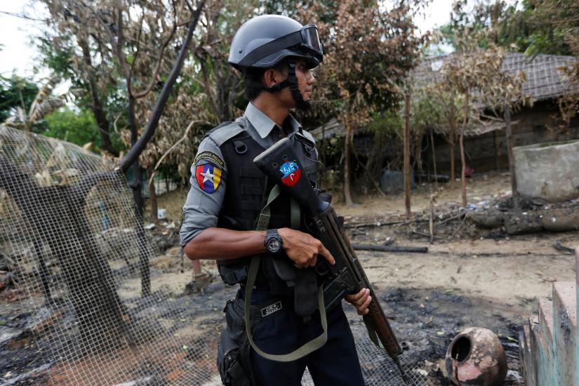 A police officer guards near a house which was burnt down during the last days of violence in Maungdaw, northern Rakhine State, Myanmar August 30, 2017. RETUERS