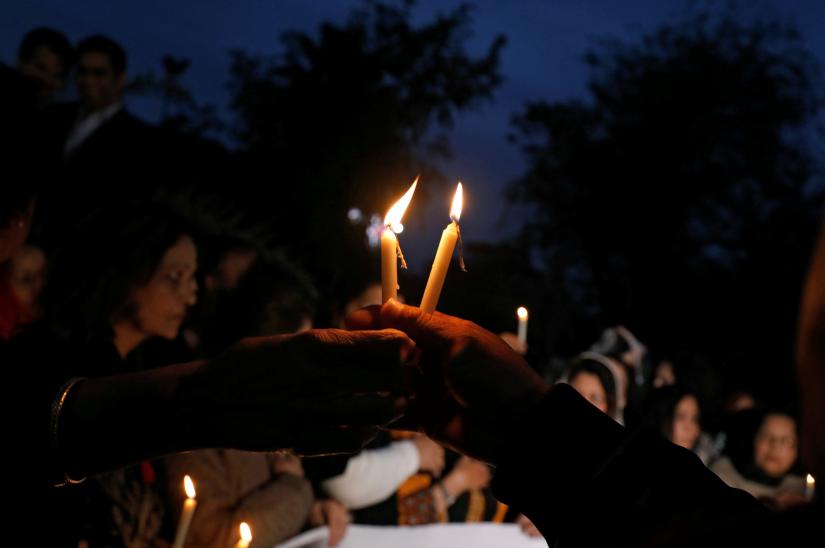 People pass candles as they gather to attend a candlelight vigil for the victims of the Christchurch mosque attacks in New Zealand, in Islamabad, Pakistan March 18, 2019. REUTERS