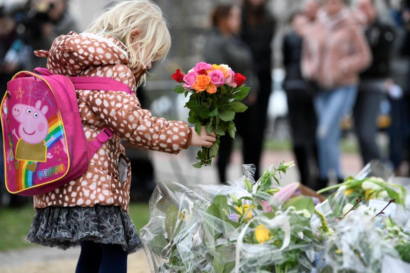 A child places flowers at a makeshift memorial at the site of a tram shooting in Utrecht, Netherlands March 19, 2019. REUTERS