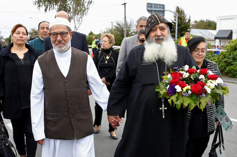 Imam Ibrahim Abdelhalim of the Linwood Mosque holds hands with Father Felimoun El-Baramoussy from the Dunedin Coptic Church, as they walk at the site of Friday`s shooting outside the Mosque in Christchurch, New Zealand March 18, 2019. REUTERS/File Photo