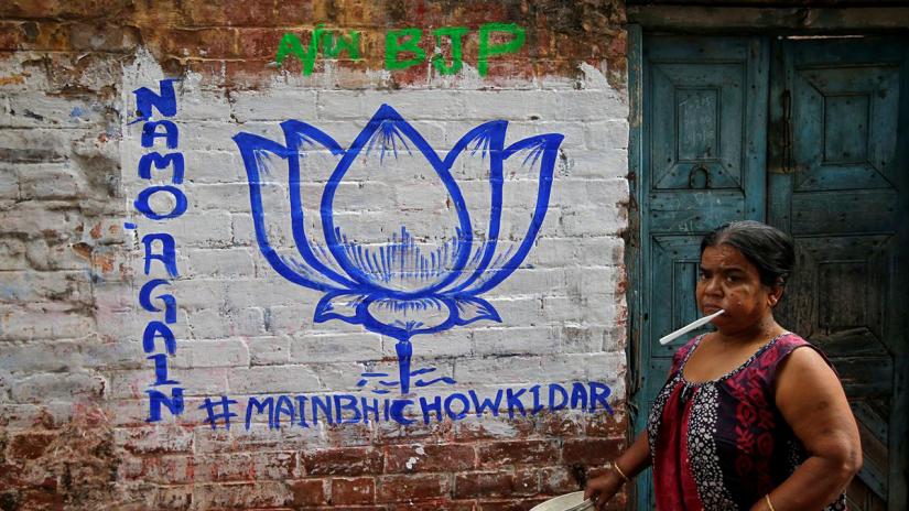 A woman walks past a wall painted with the election symbol of India`s ruling Bharatiya Janata Party (BJP) in an alley at a residential area in Kolkata, India, March 22, 2019. REUTERS