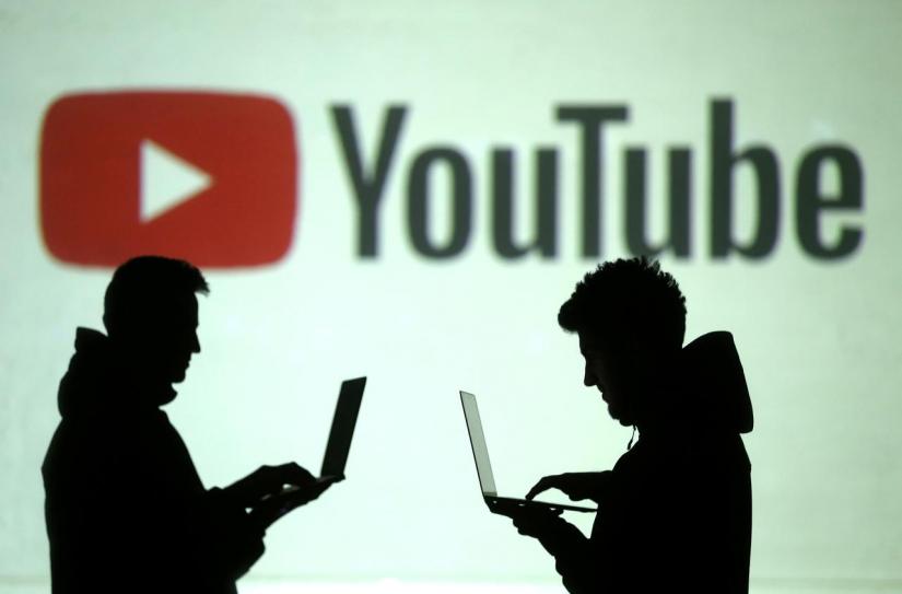 FILE PHOTO: Silhouettes of mobile device users are seen next to a screen projection of Youtube logo in this picture illustration taken Mar 28, 2018. REUTERS
