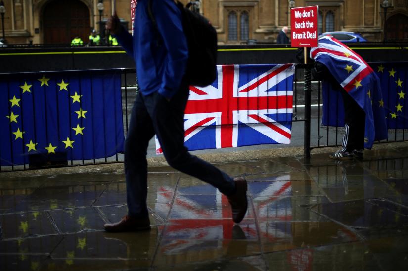 A person walks past an EU and a British flag in London, Britain, April 2, 2019. REUTERS