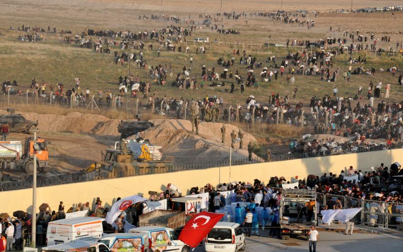 Syrian refugees from Tel Abyad (foreground) line up at the border crossing as the others wait behind the fences to cross into Turkey at the Akcakale border gate in Sanliurfa province, Turkey, June 14, 2015. REUTERS