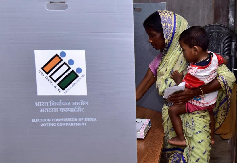 A woman holds a child as she casts her vote at a polling station during the second phase of general election in Hojai district in the northeastern state of Assam, India, April 18, 2019. 