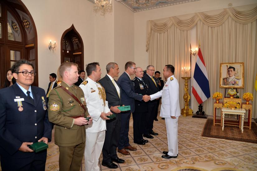 Richard Harris, Australian member of the Thai cave rescue team shakes hands with Thailand`s Prime Minister Prayuth Chan-ocha, next to Craig Challen after receiving the Member of the Most Admirable Order.