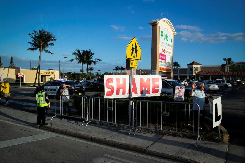 A protestor holds a sign as U.S. President Donald Trump`s motorcade heads to his Mar-a-Lago club, in West Palm Beach, Florida, U.S., April 18, 2019