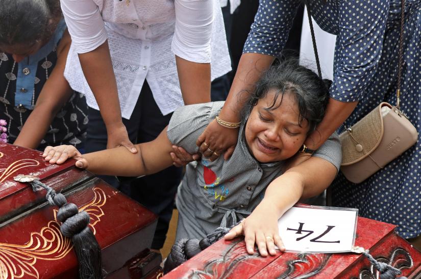 A woman reacts next to two coffins during a mass burial of victims, two days after a string of suicide bomb attacks on churches and luxury hotels across the island on Easter Sunday, at a cemetery near St. Sebastian Church in Negombo, Sri Lanka April 23, 2019. REUTERS