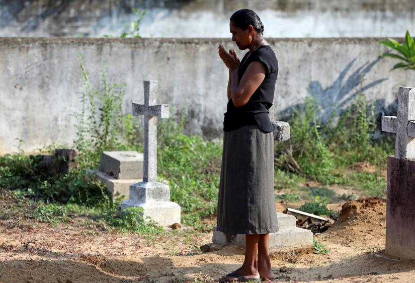 A woman prays at a cemetery, as victims of a string of suicide bomb attacks on churches and luxury hotels on Easter Sunday are being buried, in Negombo, Sri Lanka April 24, 2019. REUTERS