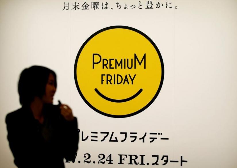 A woman walks past the logo of Premium Friday campaign, encouraging firms to let workers out a few hours early on the last Friday of every month so that they spend money on shopping and leisure to help boost the economy, in Tokyo, Japan, February 21, 2017. Picture taken February 21, 2017.