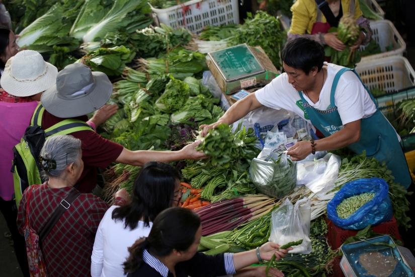 FILE PHOTO: People shop for vegetables at a market in Kunming, Yunnan province, China May 9, 2019. REUTERS