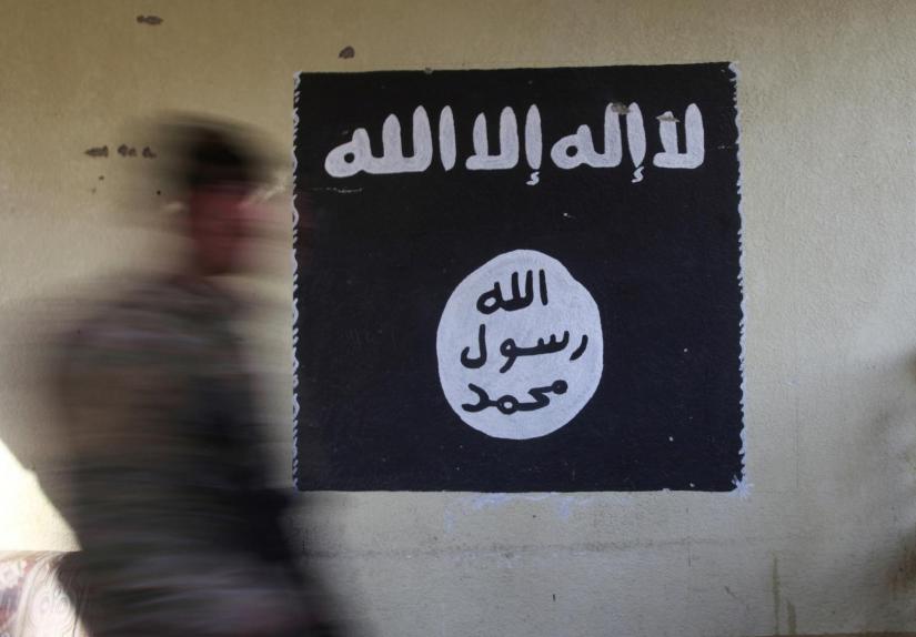 FILE PHOTO: A member of the Iraqi rapid response forces walks past a wall painted with the black flag commonly used by Islamic State militants, at a hospital damaged by clashes during a battle between Iraqi forces and Islamic State militants in the Wahda district of Mosul, Iraq, January 8, 2017. REUTERS