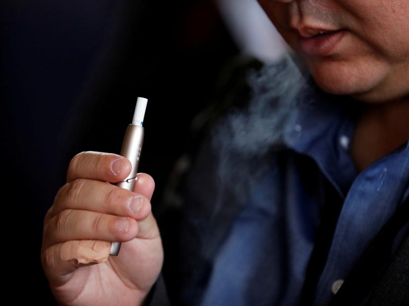 FILE PHOTO: A man tries Philip Morris` IQOS 3 device after its launching event in Tokyo, Japan, October 23, 2018. REUTERS