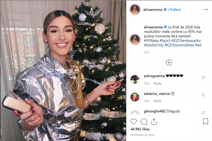 Alina Eremia, a Romanian actress and singer whose biography gives her age as 25, holds a gold-colored IQOS device in front of a Christmas tree as part of a campaign by Philip Morris International to market the device in an Instagram post December 29, 2018. Alina Eremia/Social Media via REUTERS.